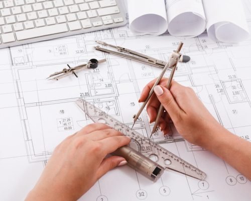 Architect drawing architectural project. Unrecognizable designer hands working with building blueprint, copy space