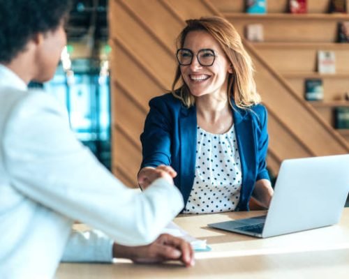 Business people shaking hands in the office. Group of business persons in business meeting. Two entrepreneurs on meeting in board room. Corporate business team on meeting in modern office. Female manager discussing new project with her colleagues. Company owner on a meeting with her employee in her office.
